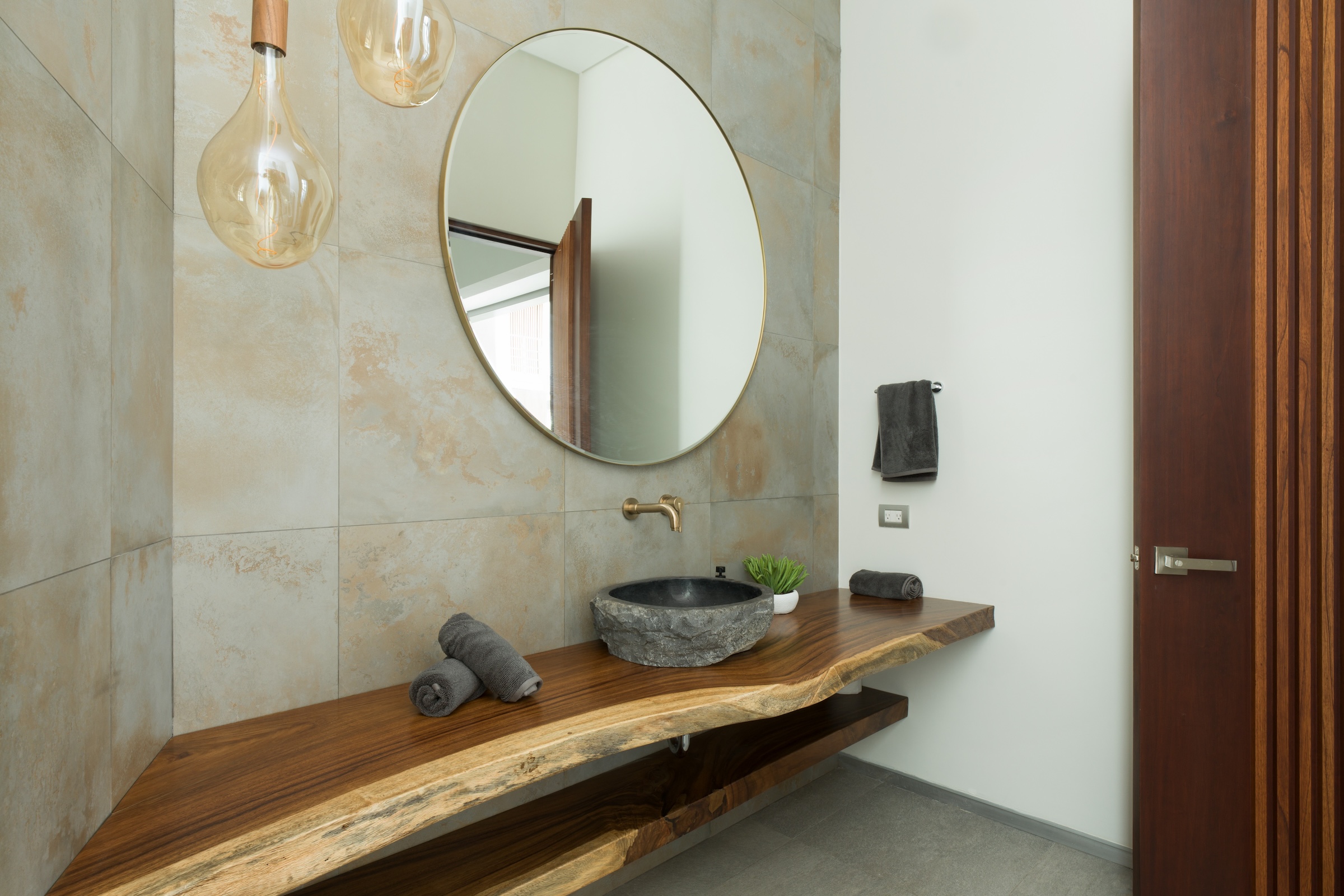 Live-edge wood bathroom vanity with stone vessel sink at Sky’s Edge