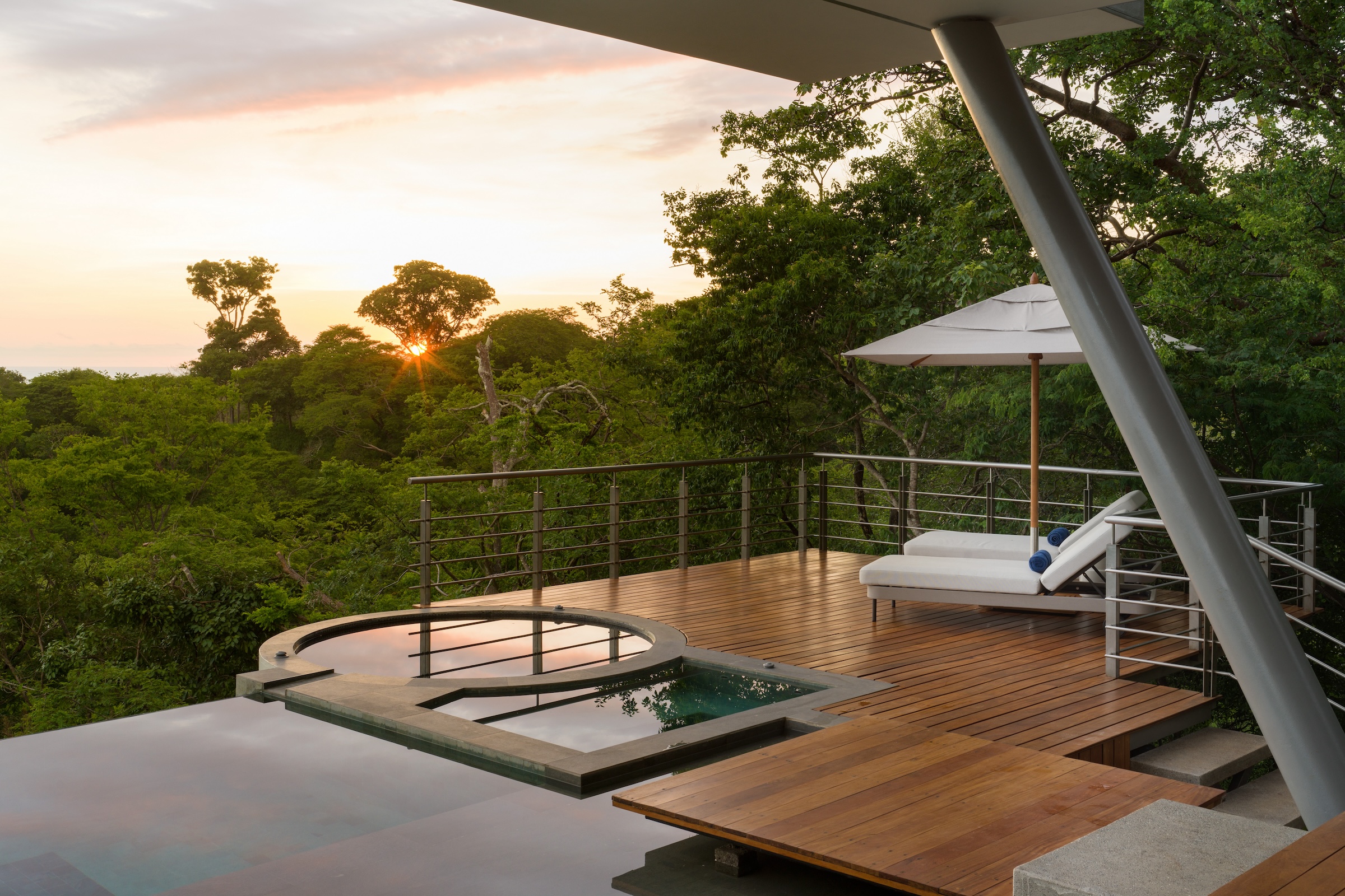 Private outdoor deck surrounded by tropical forest at sunset at Sky’s Edge